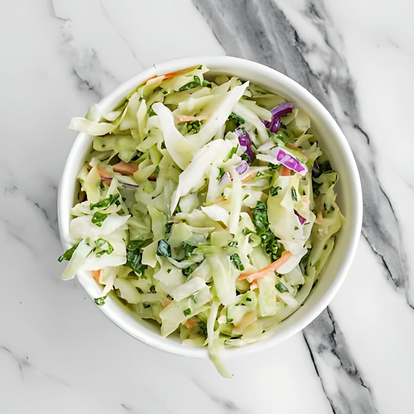 Sumah Hot Chicken's coleslaw, a white bowl filled with shredded cabbage, carrots, and purple cabbage.